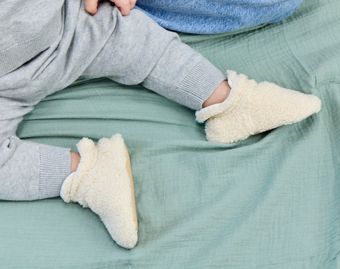 Child sitting wearing Ten Little Sherpa Baby Booties. Available at www.tenlittle.com