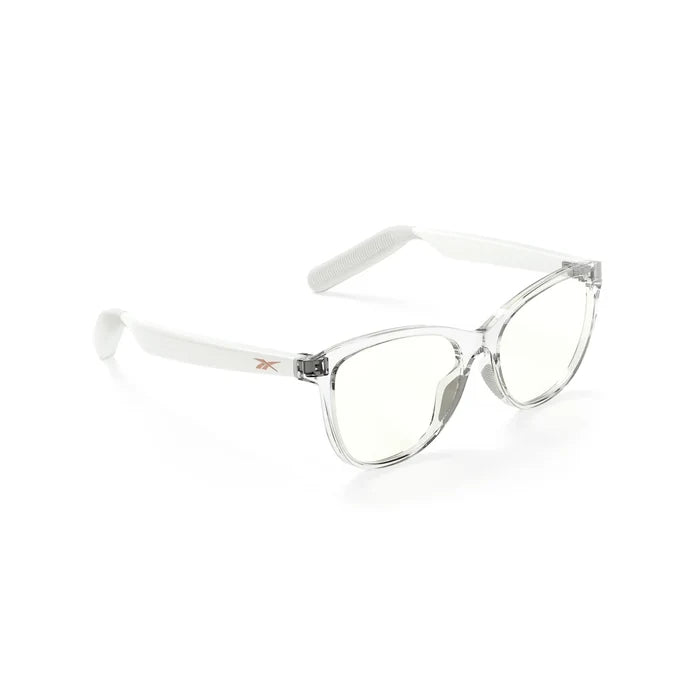 The Reebok Shine smart eyewear features clear frames, slightly tinted lenses, and white arms with open-ear audio. Displayed at a three-quarter angle on a white background.