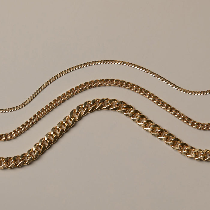 Model Three gold chain necklaces on a beige background