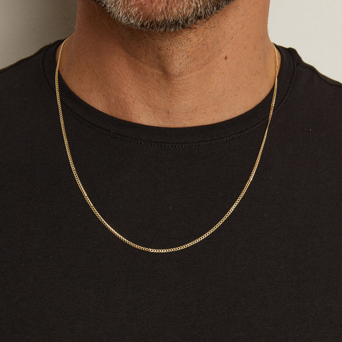 Model. Gold chain necklace worn by a person on a plain background