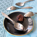 Bouchée au chocolat sur une soucoupe noire et or, avec des cuillères décorées tsé tsé