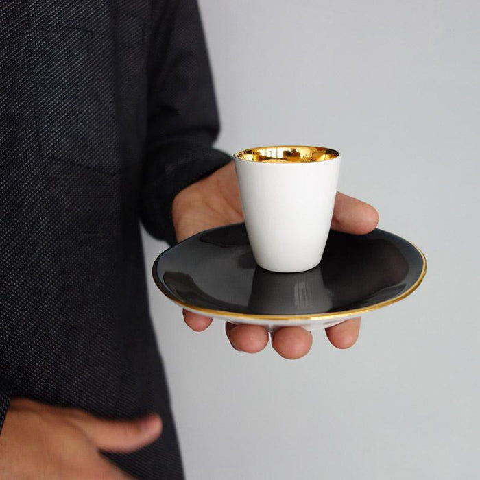 tasse à expresso posée sur une sous-tasse en porcelaine noire et or - tsé tsé