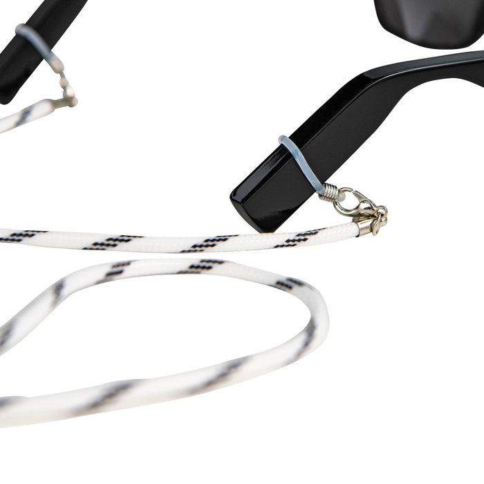 Close-up of a black Lucyd eyeglass arm with the Sport Strap—featuring a white and black pattern, silver clasp, and rubber loop—securely attached on a white background; ideal for keeping your Lucyd frames stylish and secure.