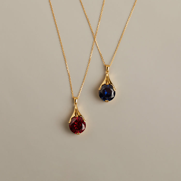 Model. Two gold necklaces with gemstone pendants on a beige background