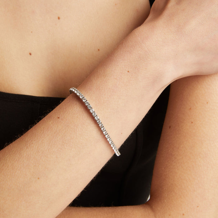 Tennis bracelet on a wrist with a black top.
