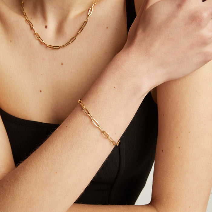 Gold chain bracelet on a person's wrist with a neutral background.